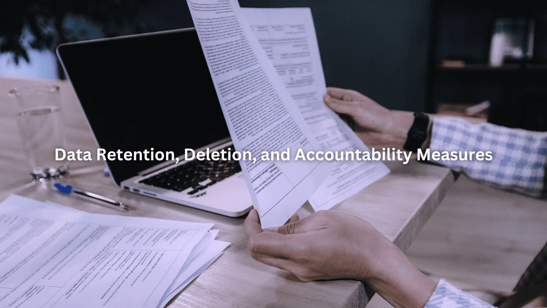 Person reviewing detailed documents at a desk with a laptop, focusing on GDPR compliant sales database policies and regulations.