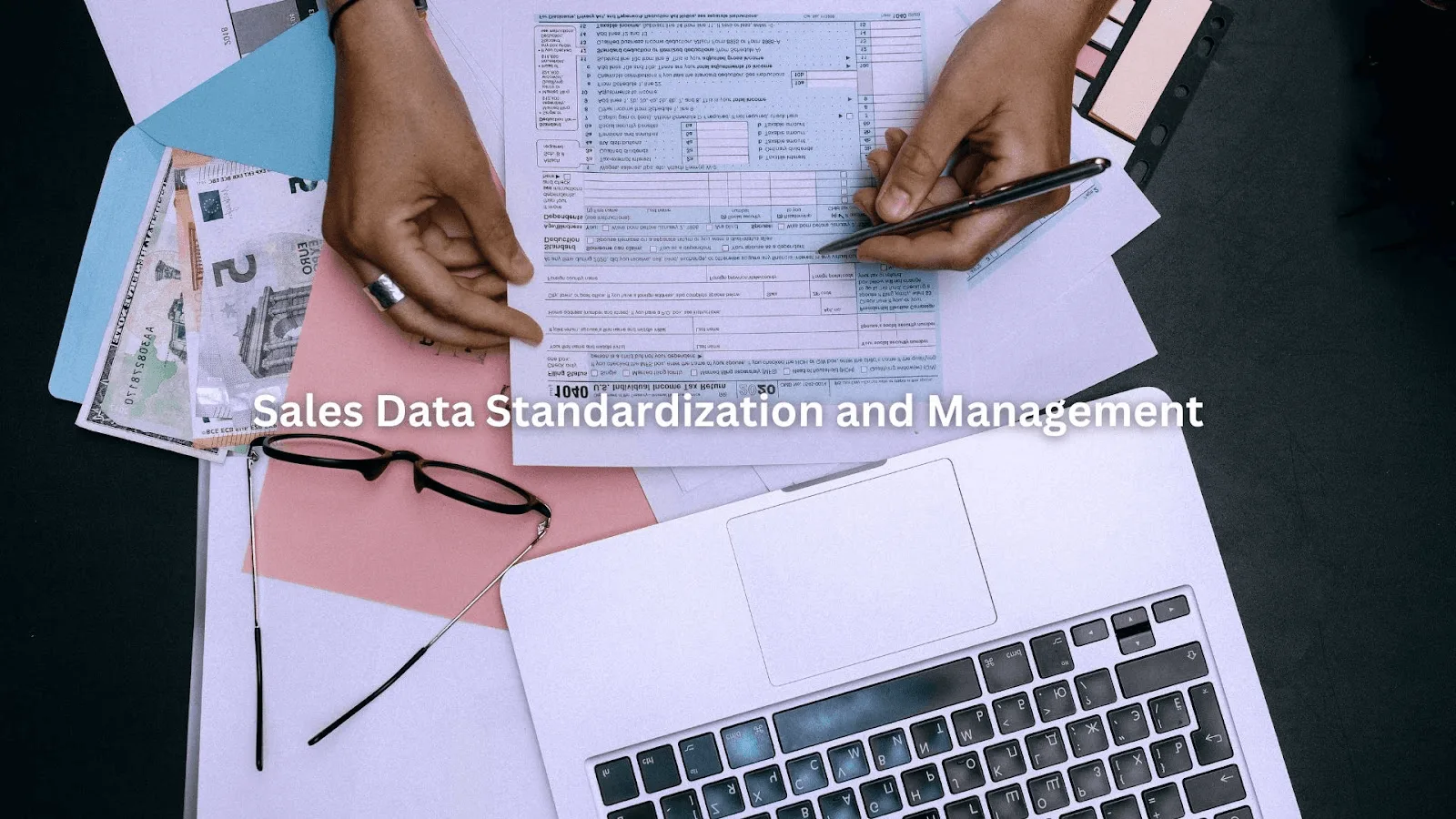 Person reviewing documents and using a laptop, focused on Wyoming sales database cleanup and data accuracy.