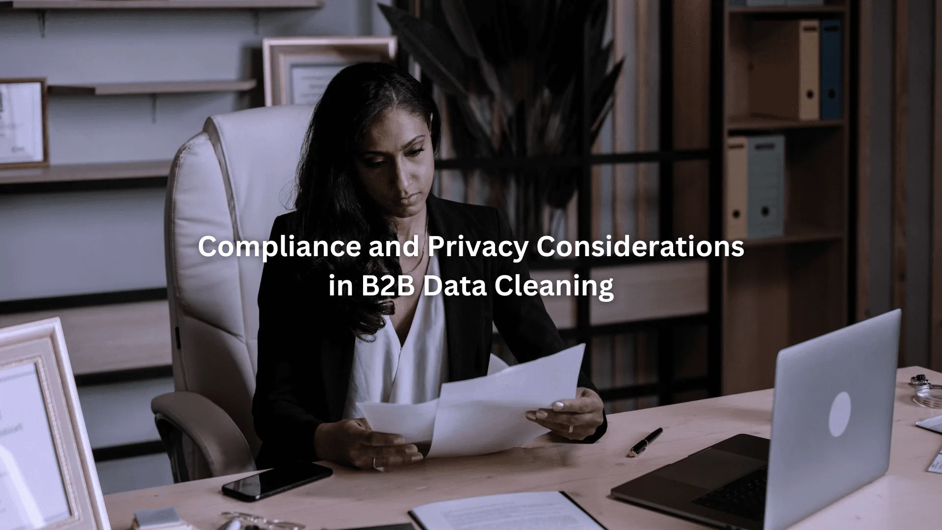 Businesswoman reviewing documents at desk, highlighting the importance of clean B2B contact data.
