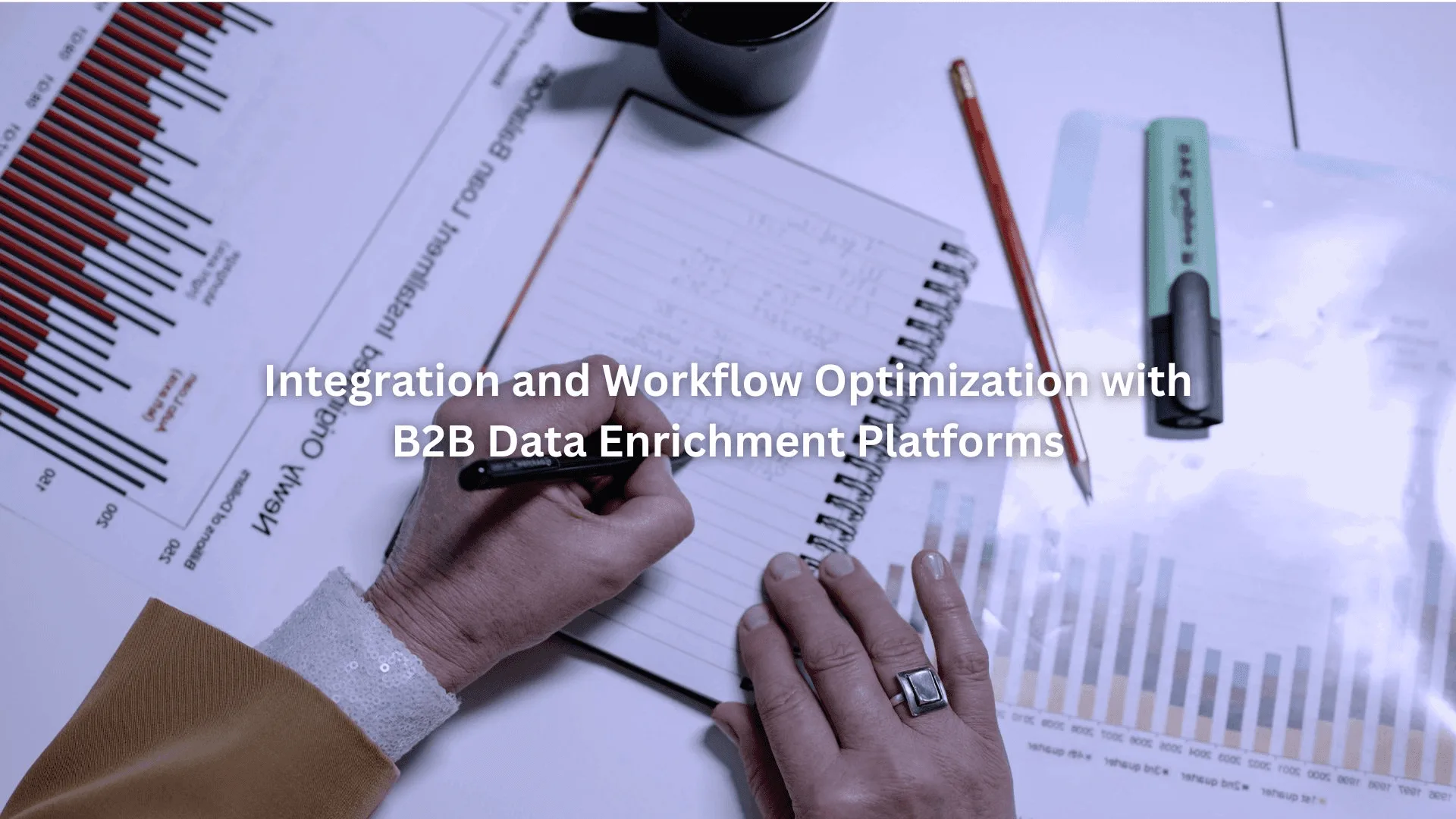 Person writing notes on a pad surrounded by charts and graphs, showcasing b2b data enrichment tools in use.