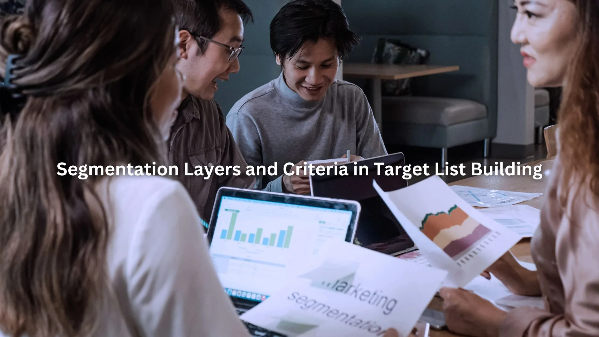 Four people working together on a marketing presentation, examining charts and documents.